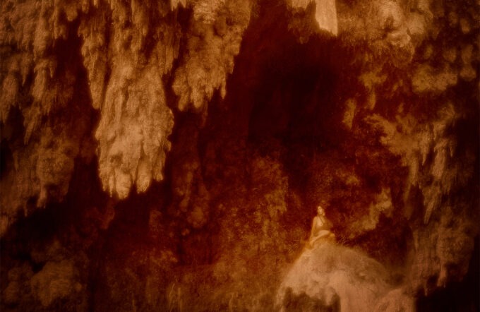 woman sitting naked on rock under waterfall
