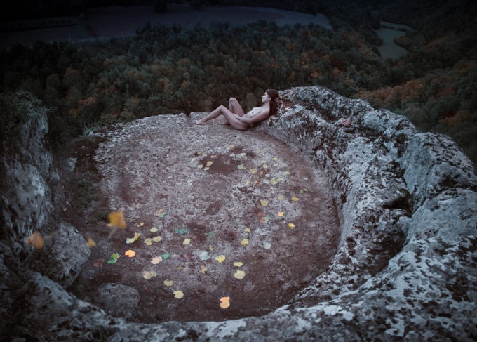 Girl in vortex of leaves on rock